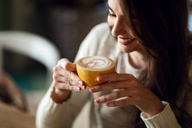 Young smiling woman holding cup of latte coffee.