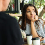 Tired bored girl sitting and drinking coffee