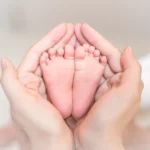 close-up-newborn-baby-feet-female-hands_33799-4092